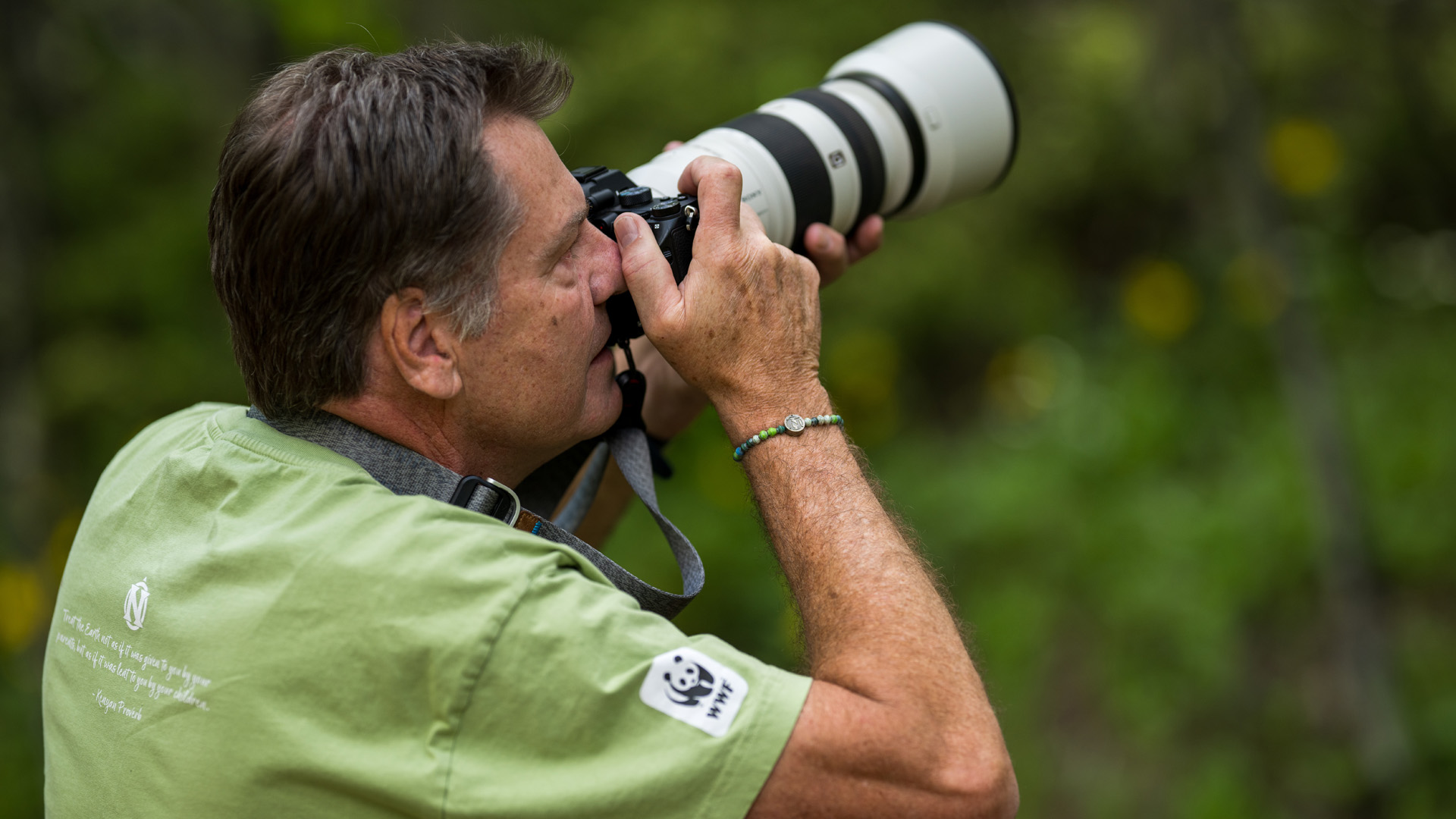 man wearing WWF panda world wildlife fund shirt photographs nature
